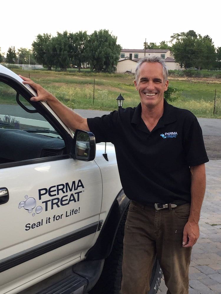 01-1-1 A smiling man in a black "PERMA TREAT" shirt leans on a white truck with "Seal it for Life!" on its side.