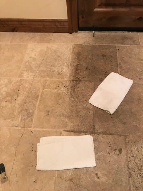 IMG_5509b-e1648502634584 Two white towels lie on a dirty tiled floor, with a clean section visible under the top towel.