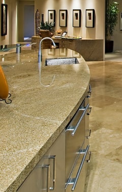 A modern kitchen island with a curved granite countertop, a faucet, and stainless steel drawers.