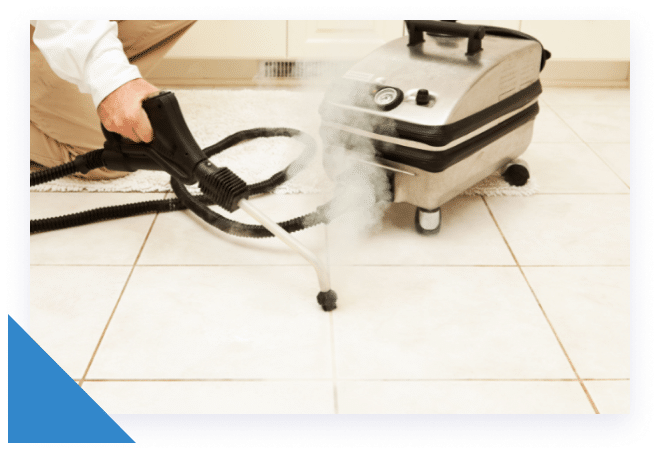 A person's hand holds a black steam cleaner, emitting steam onto light-colored tiled flooring.