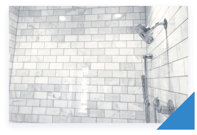 A white tiled shower with a chrome showerhead and a handheld shower wand on the right.