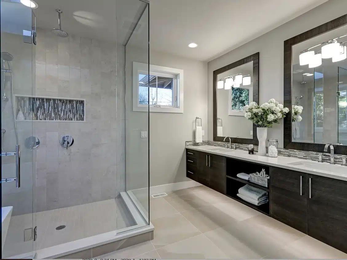 A modern bathroom features a glass shower stall and a floating dark wood vanity with two sinks and mirrors.