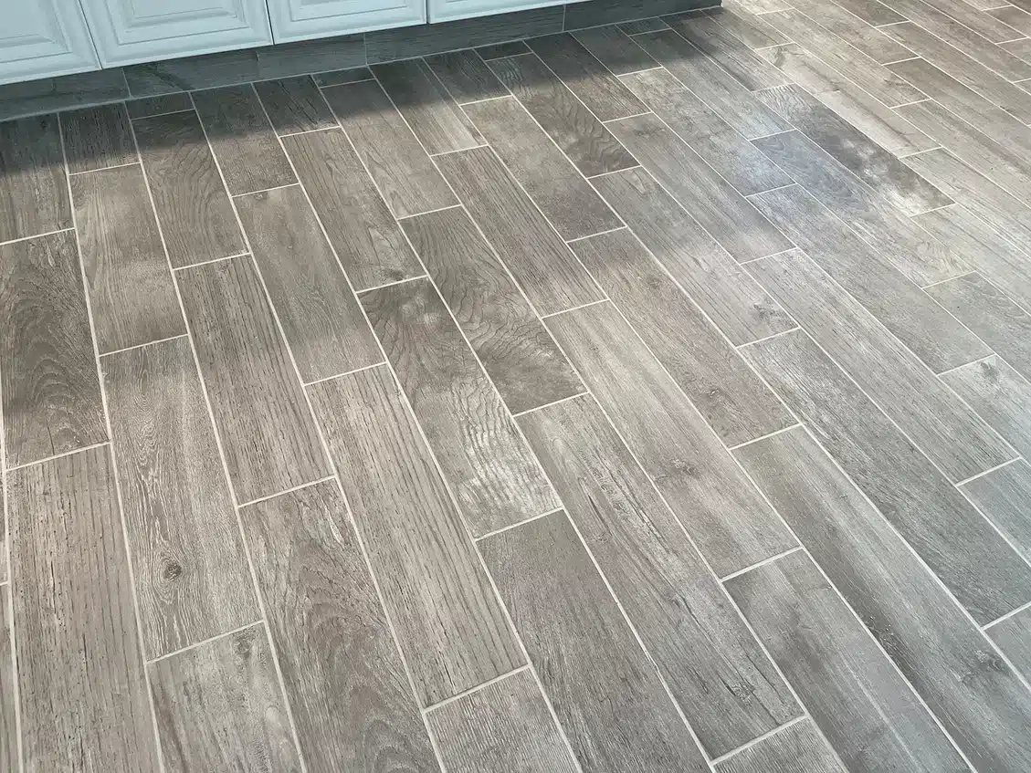 A tiled floor with long, narrow, light gray planks resembling wood grain, with white grout lines.