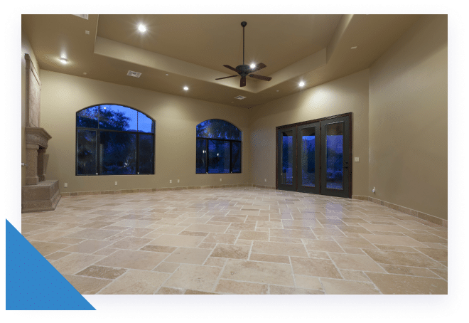 An empty room with light tan walls, a tiled floor, two arched windows, a fireplace, and a ceiling fan.